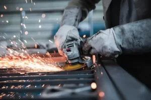 Chinese manufacturing worker grinding metal in factory during supplier verification inspection process