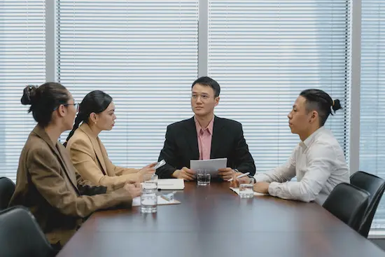 Professional team engaged in a business meeting around a conference table, representing leoker's expertise in facilitating supplier communication, negotiation support, and strategy development for optimal client outcomes.