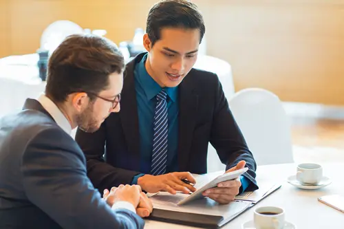 Two business professionals discussing trade consulting strategies provided by leoker, focusing on supplier evaluation, risk management, and market entry for success in the chinese market.