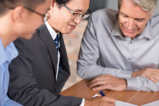 Business professionals discussing and reviewing legal documents at a table, representing leoker's expertise in legal protection, intellectual property enforcement, and robust legal frameworks to safeguard client interests.